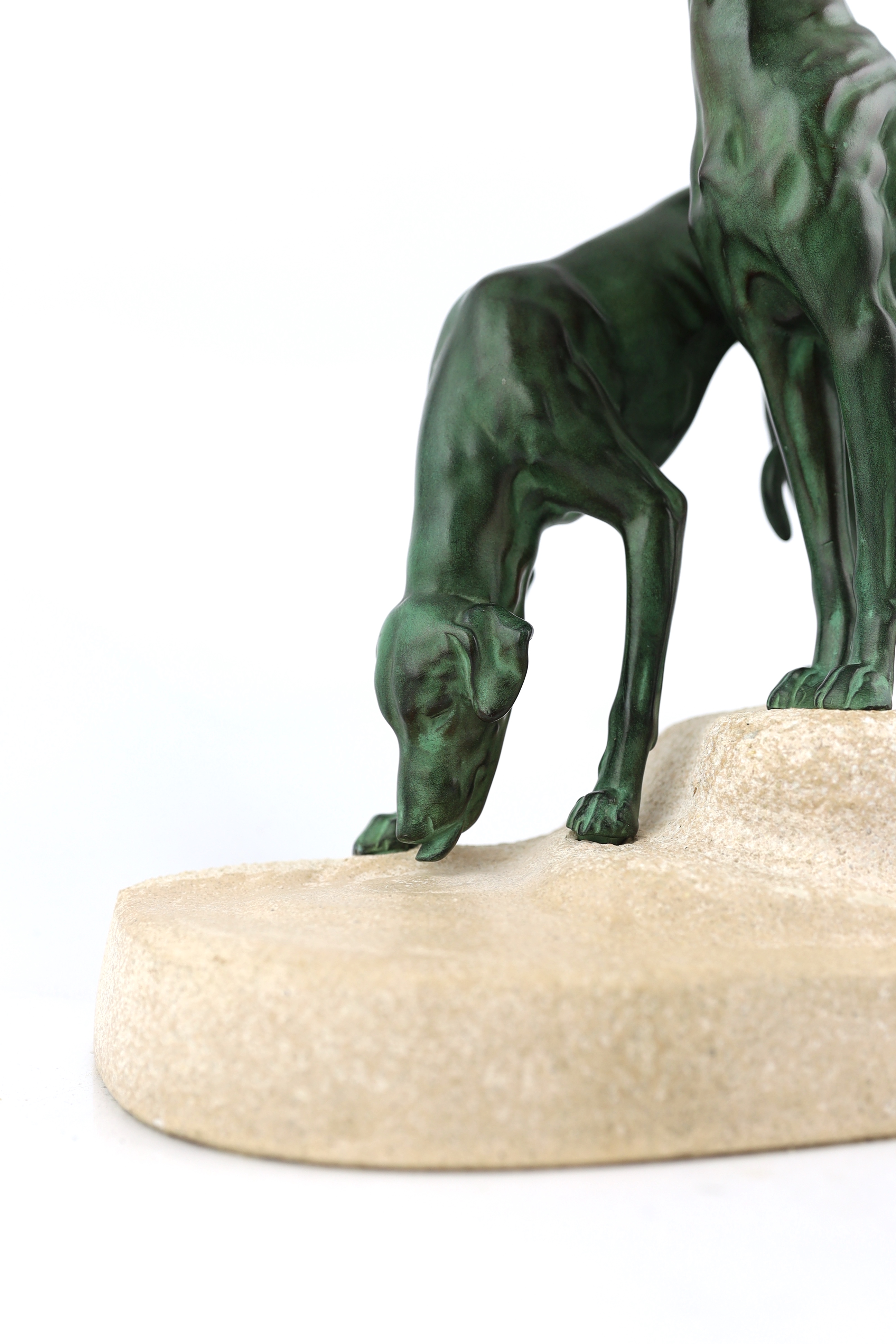 Masson, a French Art Deco spelter and composition stone group of two hounds watering, signed in the base, 32cm long, 12cm deep, 28cm high